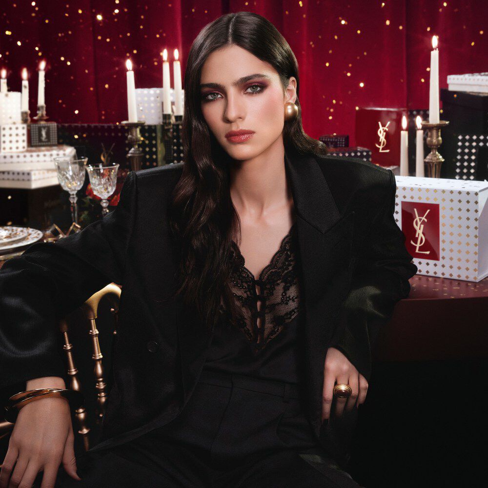 YSL Holiday 2026 makeup collection and fragrance set on gold-dotted white pedestals in burgundy.