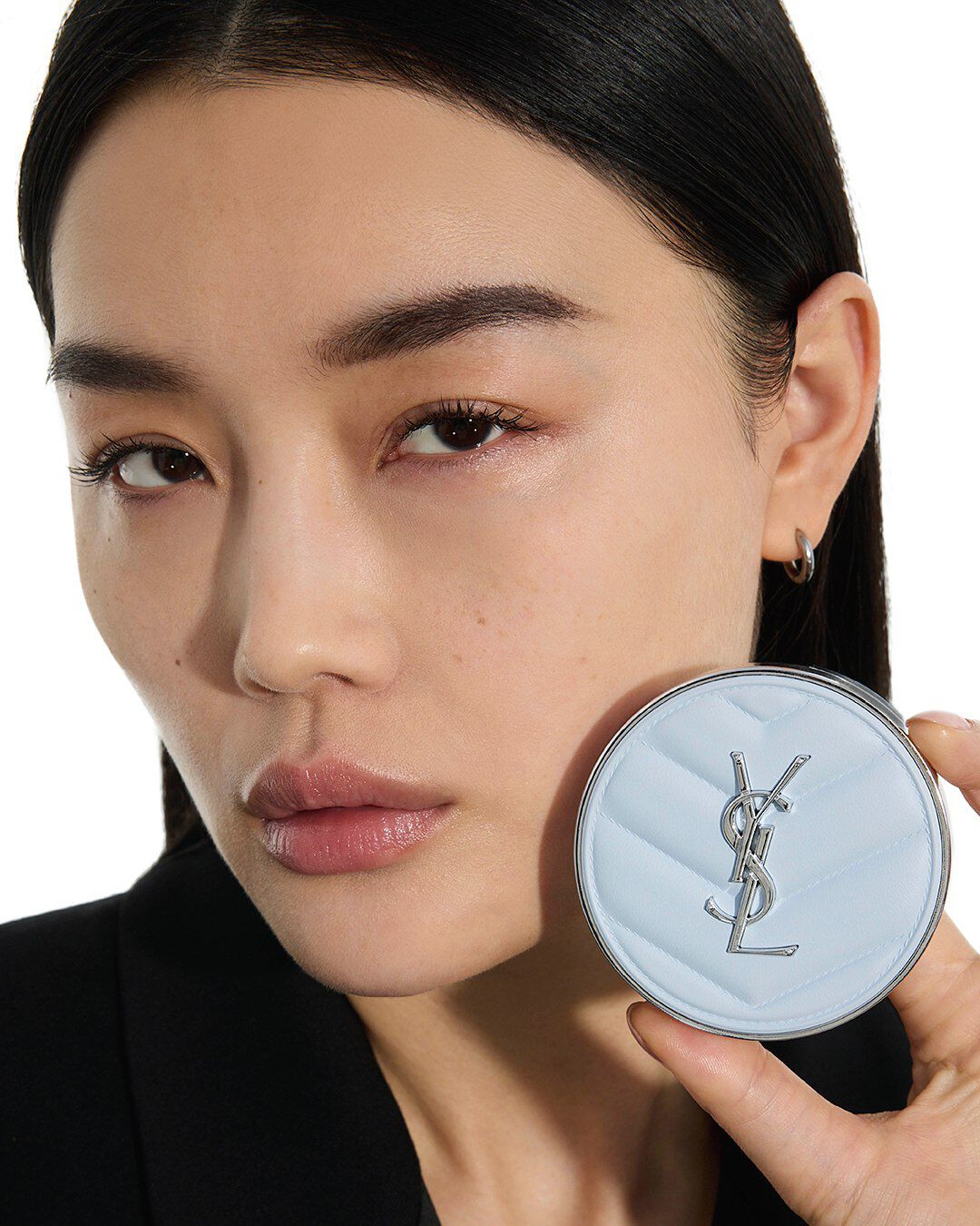 Mei J, YSL Beauty model, holding YSL All Hours Blur Cushion, showcasing its sleek light blue quilted design.