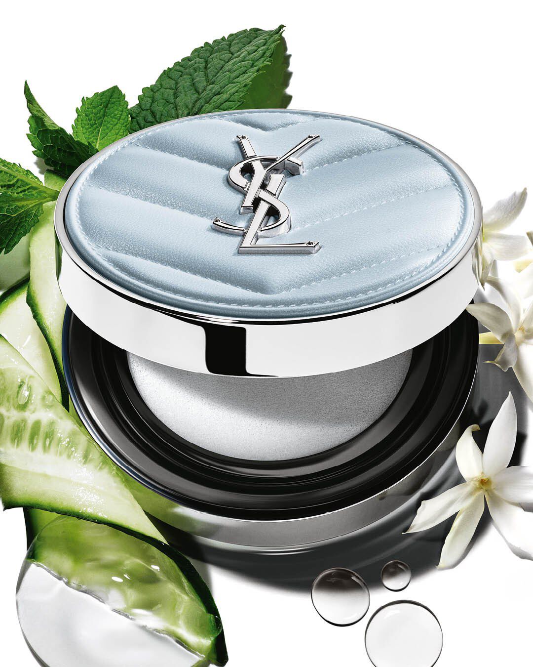 YSL All Hours Blur Cushion, light blue compact, surrounded by fresh menthol, cucumber, and jasmine flowers.