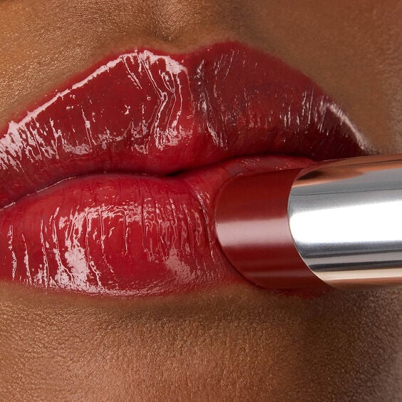 Close-up of YSL LOVESHINE Lipstick in Berry Crush, shade 219, being applied to model Zahara's glossy, vibrant red lips.