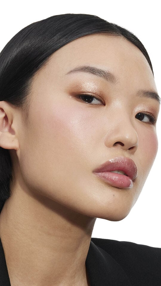 Nyaluak, deep-skinned, with YSL LOVESHINE Plumping Lip Oil Gloss in Shade 11 Radiant Glass, showcasing glossy lips.