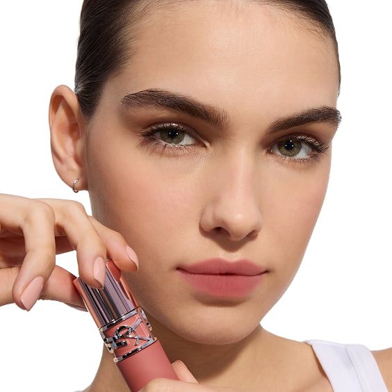 Fair skin tone model holding the YSL
LOVENUDE LIP STAIN bottle next to her
face.