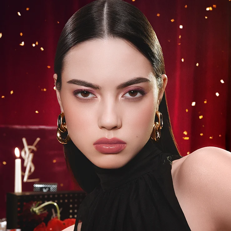 Libre Santal Couture bottle on a desk with a YSL leather pouch, a notebook, and a gold mirror.