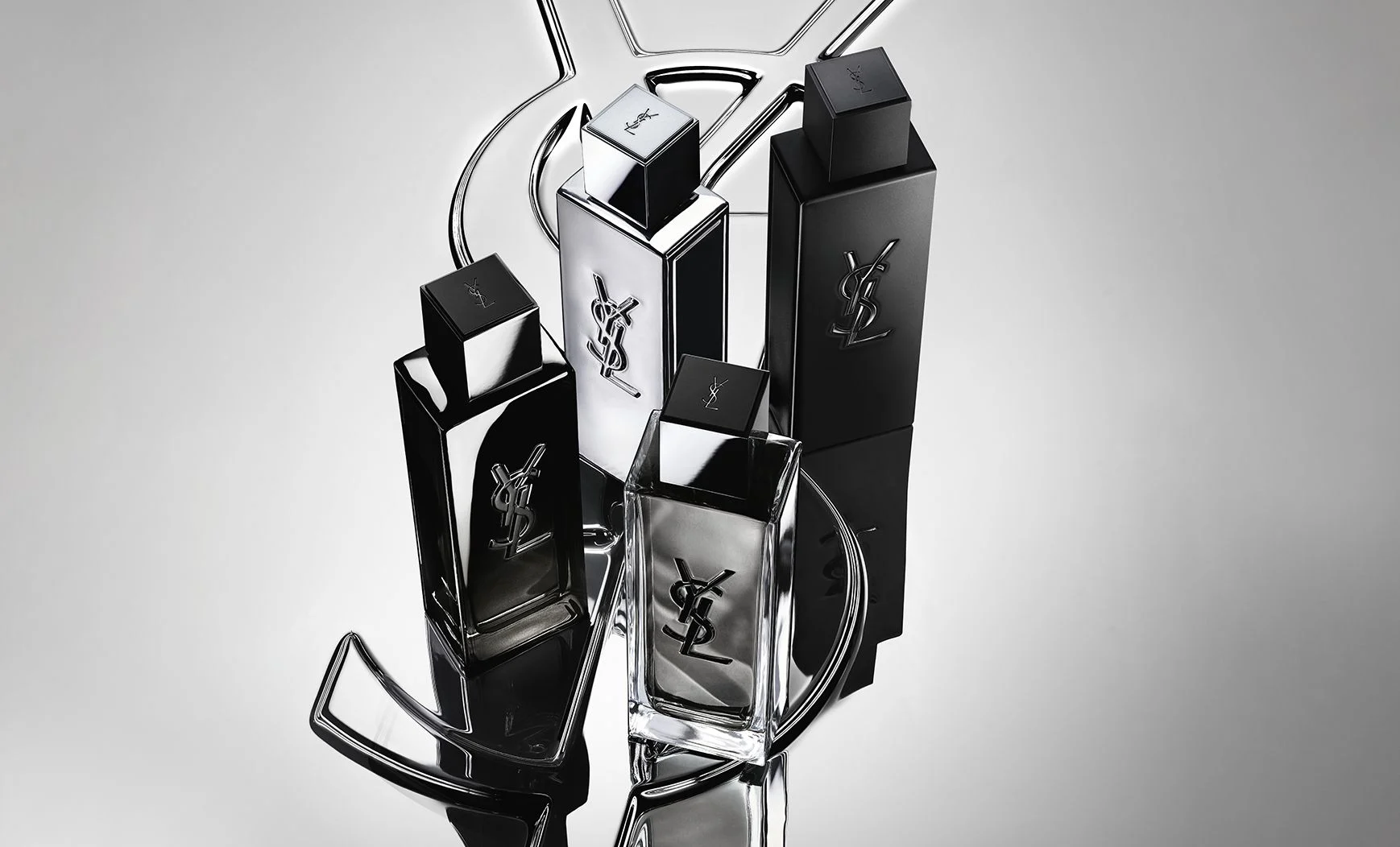 Group shot of the complete MYSLF fragrance range bottles standing on a large YSL Cassandre logo with a reflective mirror effect.